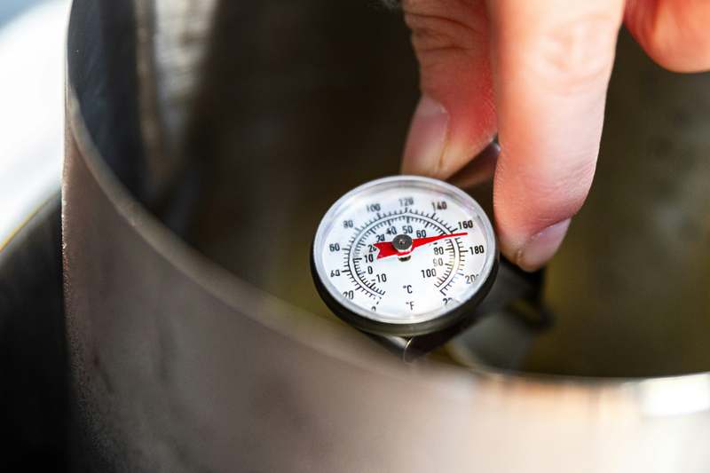Side-by-side comparison of 5 popular oven thermometers on a clean countertop, labeled with accuracy metrics and probe types